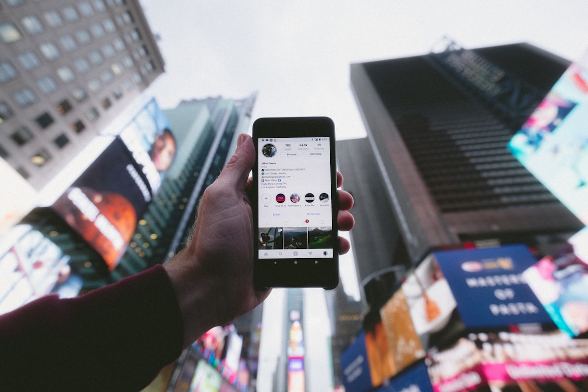 Hand holding a phone showing an influencer's Instagram profile against a New York City skyline